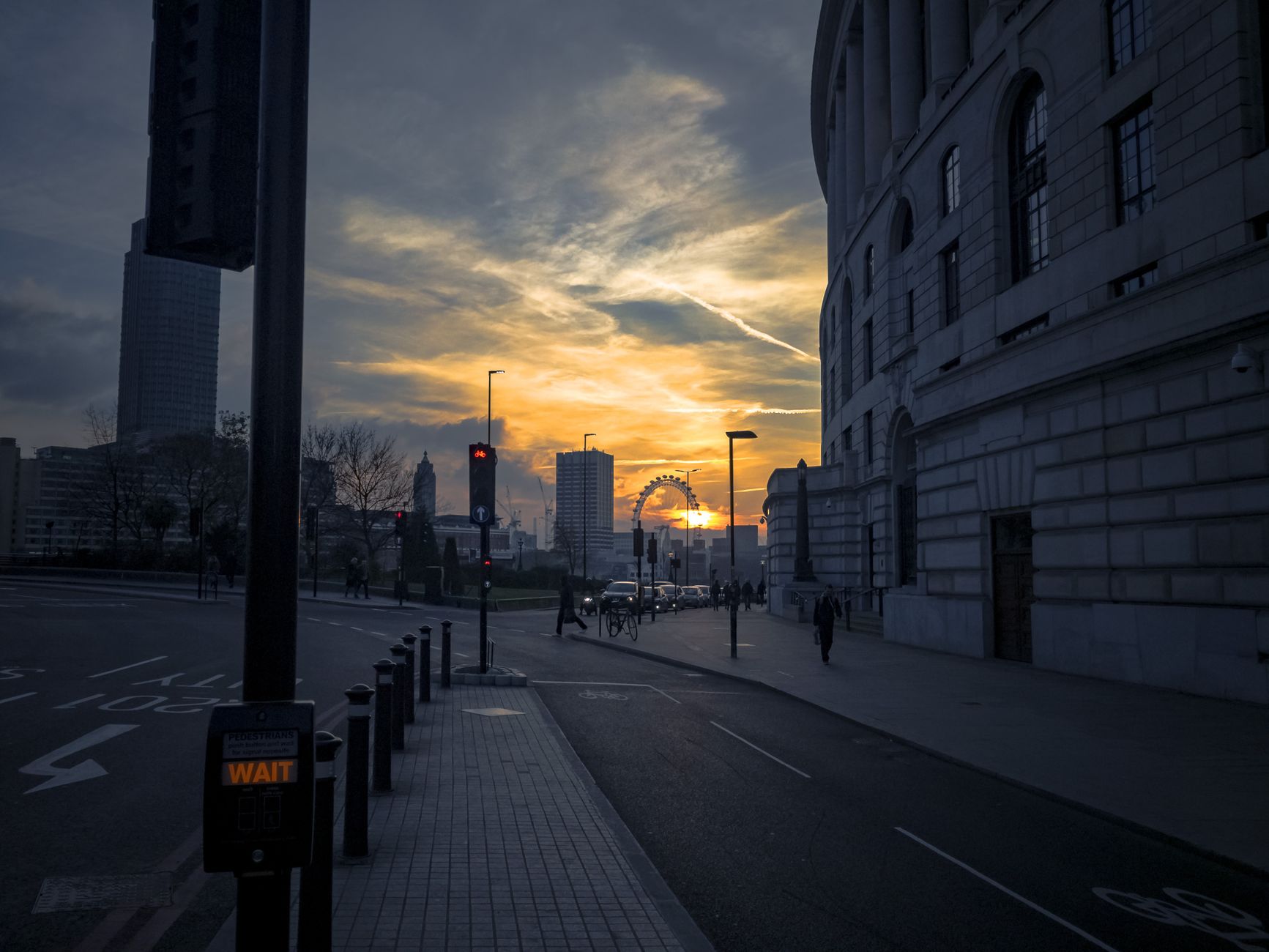 Captivating sunset with the London Eye in the background, viewed from a city street.
