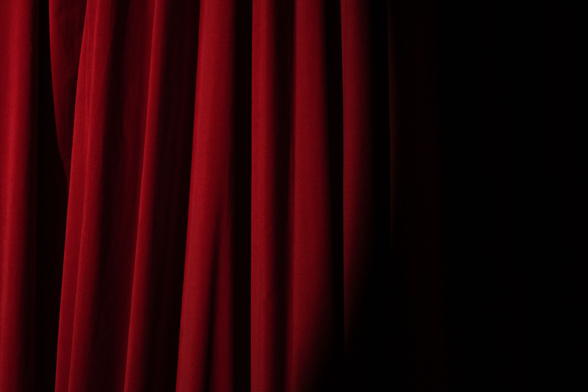 Elegant red velvet curtain with dramatic lighting perfect for theater themes.